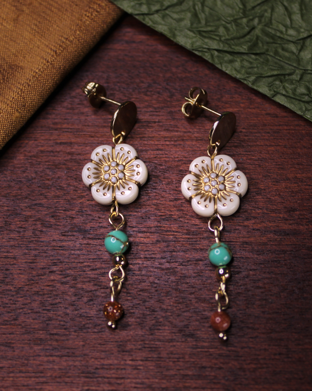 Gold colored circle earring stud with dangling bone white flower beads.
