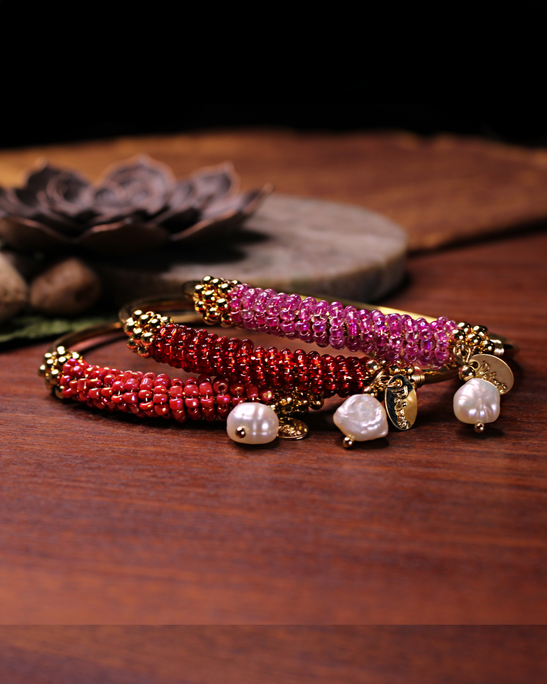 Gold colored bangle bracelet, set of three with wired gold and dark salmon, transparent red and transparent pink crystal seed beads and freshwater pearl dangling bead.