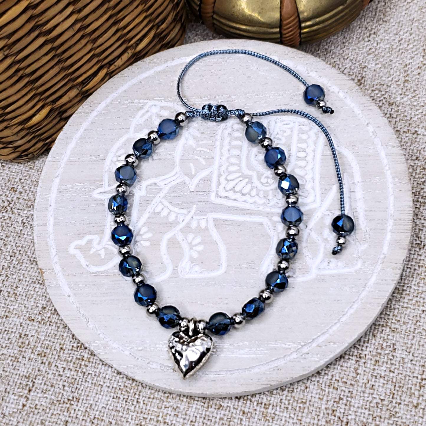 Silver colored hammered heart charm with crystal blue beads, adjustable bracelet