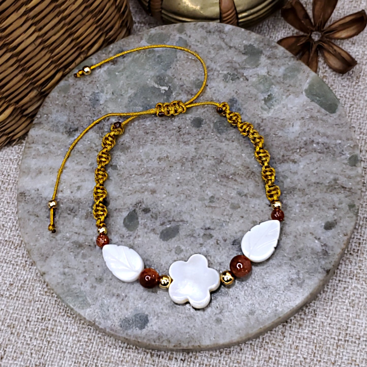 White mother of pearl flower and leaves bead bracelet, with sandstone beads accents. Adjustable gold cord macrame bracelet.