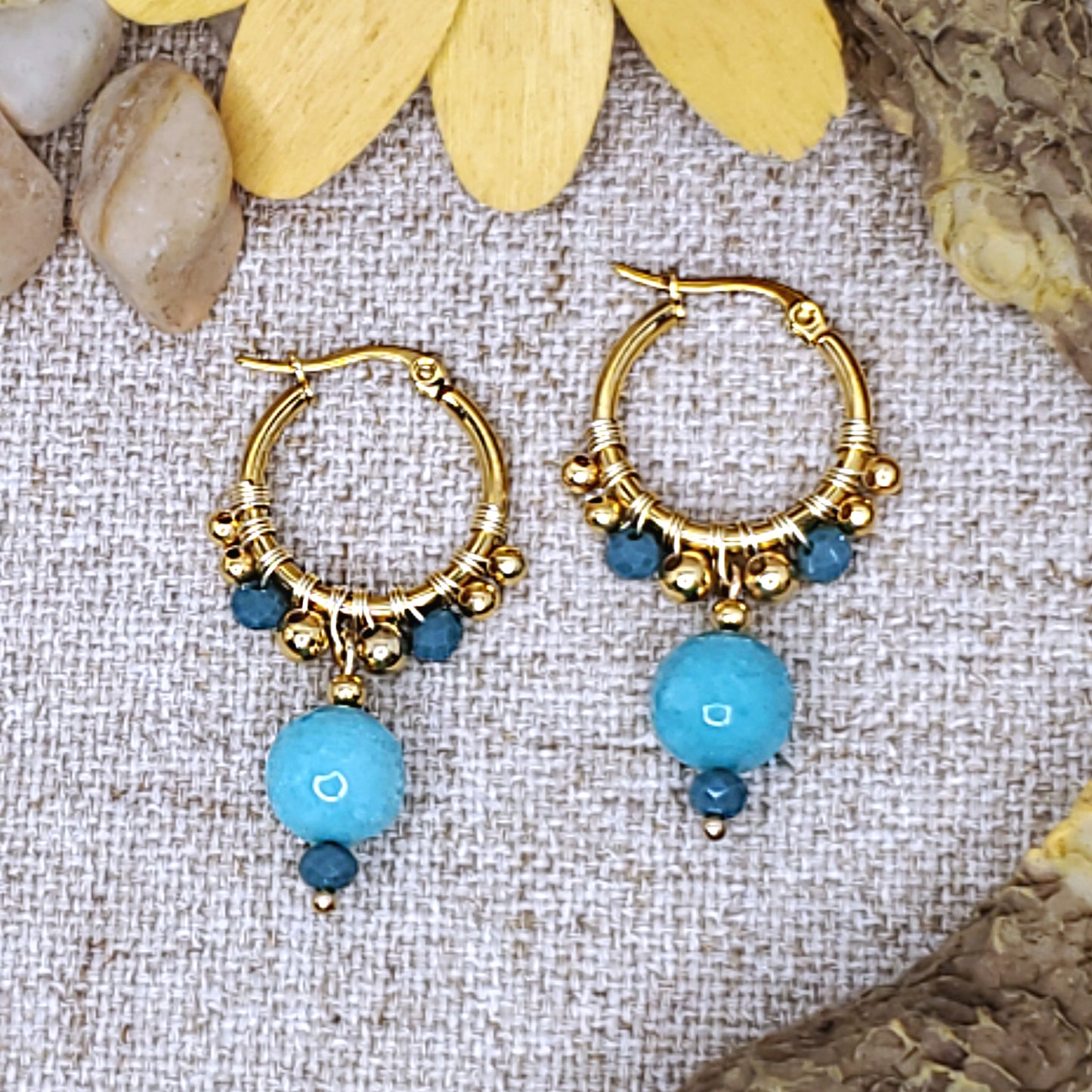 Small gold dangling hoop earrings with faceted light blue jade bead.