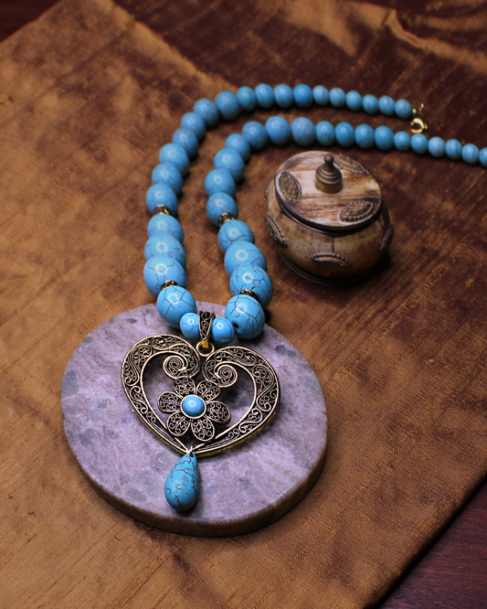 Statement turquoise color necklace with filigree antique gold heart pendant and a teardrop turquoise dangling bead. 