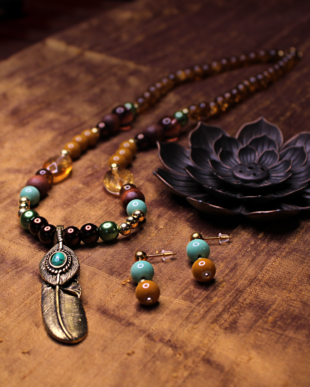 Antique gold color feather pendant necklace with seafoam green, brown, amber, gold, turquoise, olive, marigold and wooden beads. With matching earrings. 