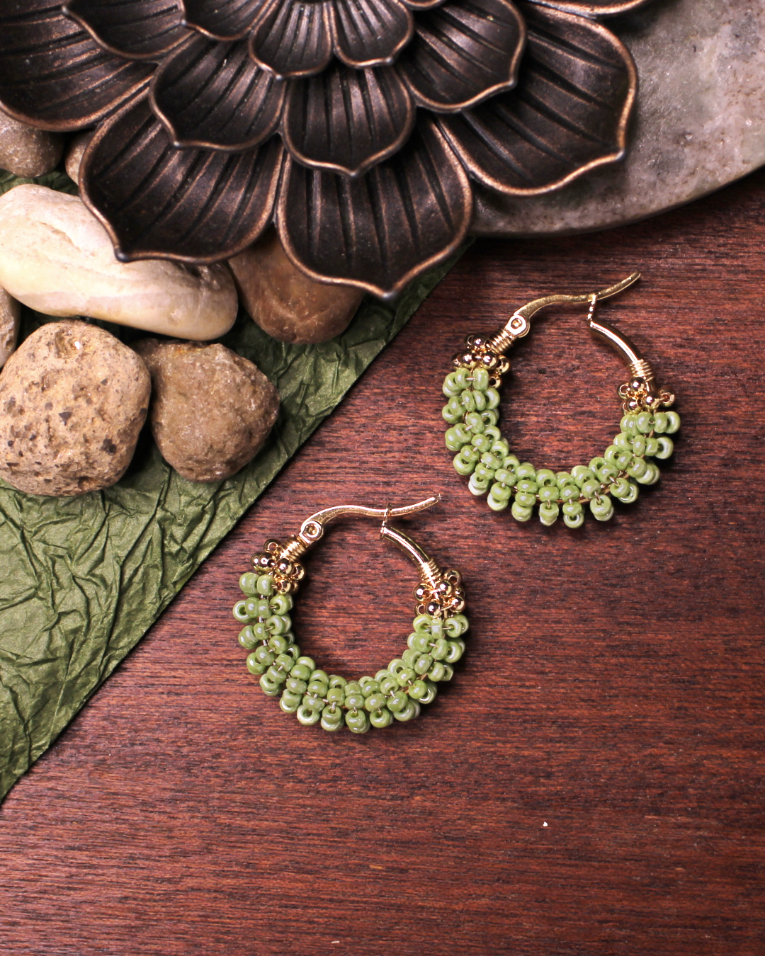 Small stainless steel gold colored hoop earrings with light green crystal seed beads.