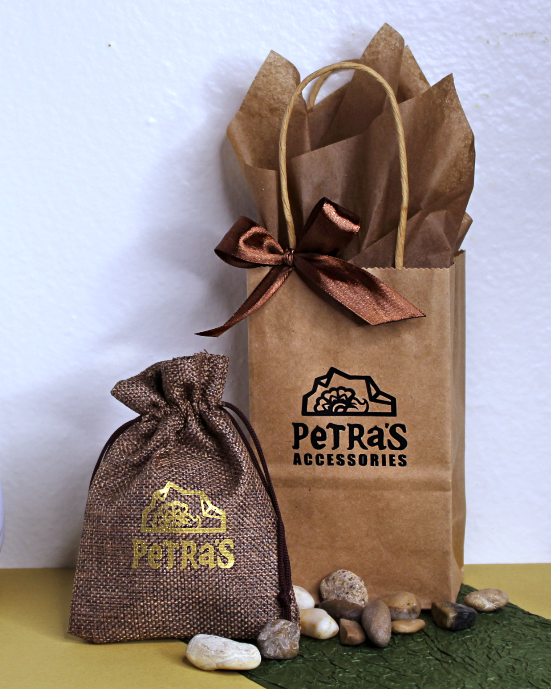 Jewelry giftwrap. Drawstring brown pouch with PeTRa'S ACCESSORIES logo. Brown kraft bag with PeTRa'S ACCESSORIES logo. Brown satin bow and brown tissue paper. 