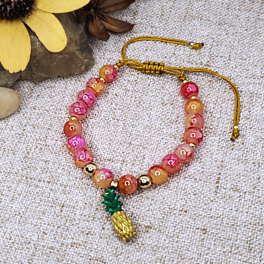 Pink and orange adjustable bracelet with a pineapple charm. 