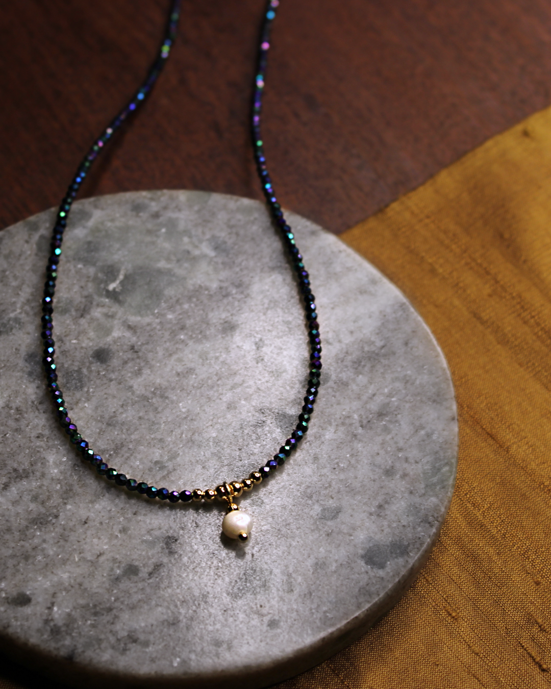 Dainty necklace with small faceted dark blue color crystal beads and dangling freshwater pearl charm.