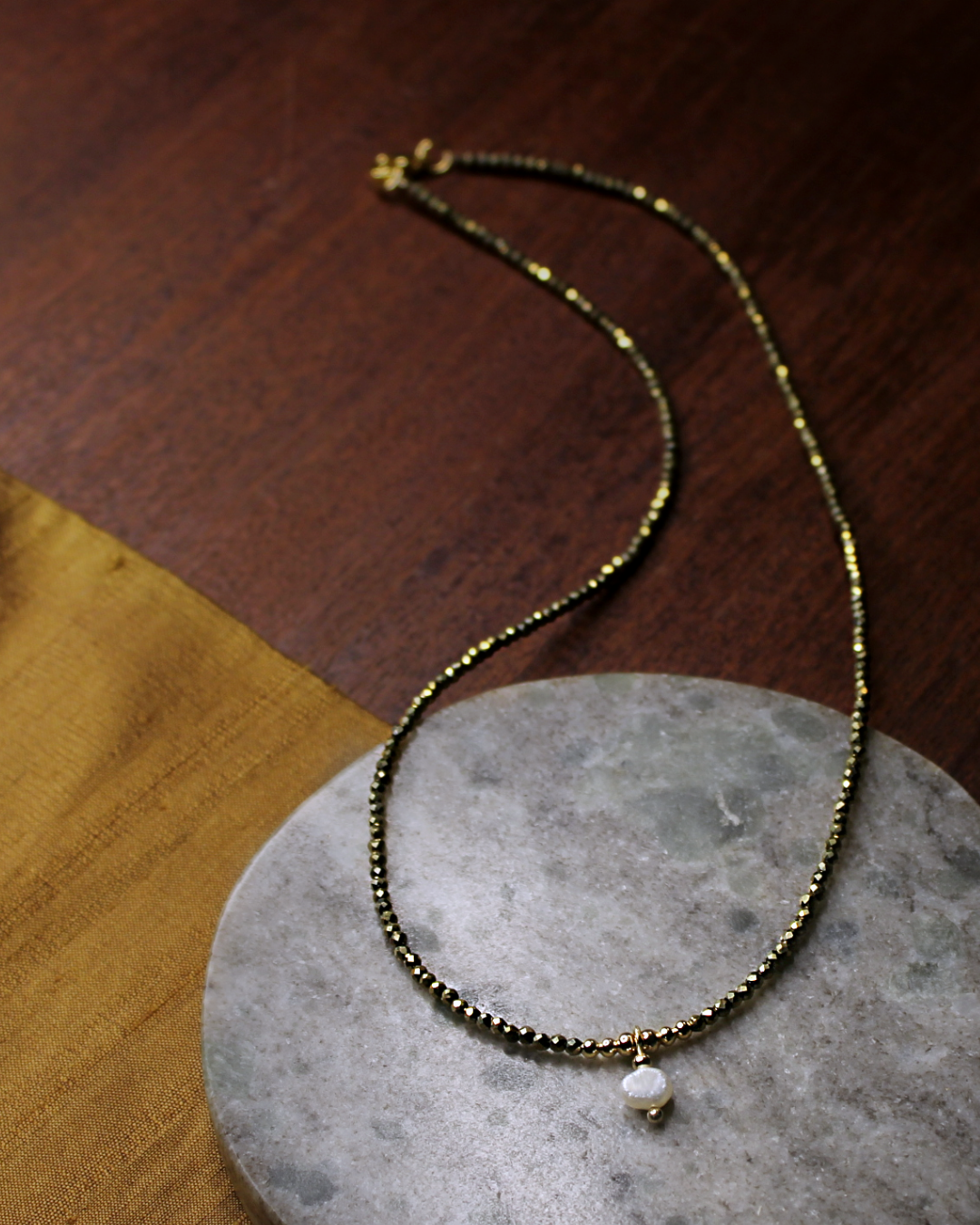 Dainty necklace with small faceted gold color crystal beads and dangling freshwater pearl charm.