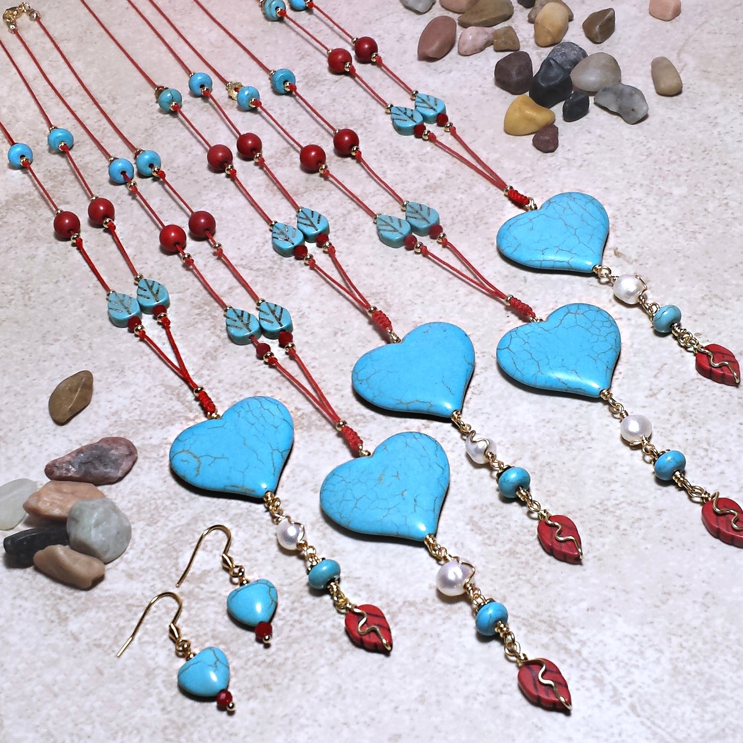Howlite heart and red string necklace set with leaf and round beads, on a beige background. 